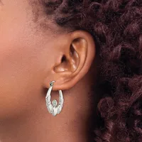 A person wearing a silver hoop earring with an oval white stone or pearl in the center, shown from the side profile against their ear.