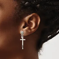 A person wearing a silver cross pendant earring with a chain attachment, shown from the side view of their ear and neck.