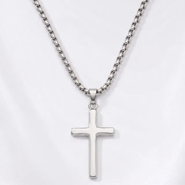 A silver cross pendant hangs from a silver box chain necklace against a white background.