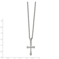 Silver-toned cross pendant with rounded ends hanging from a thin chain necklace, displayed against a measurement scale.
