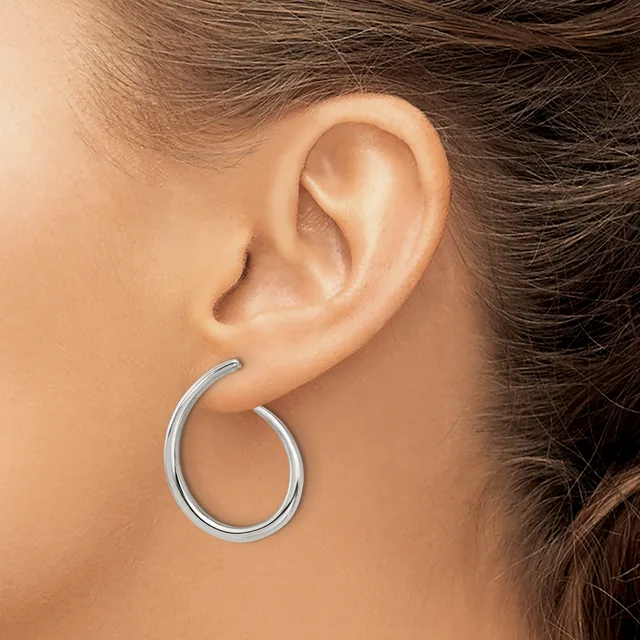 A silver hoop earring worn on a person's earlobe, shown from a side profile view.