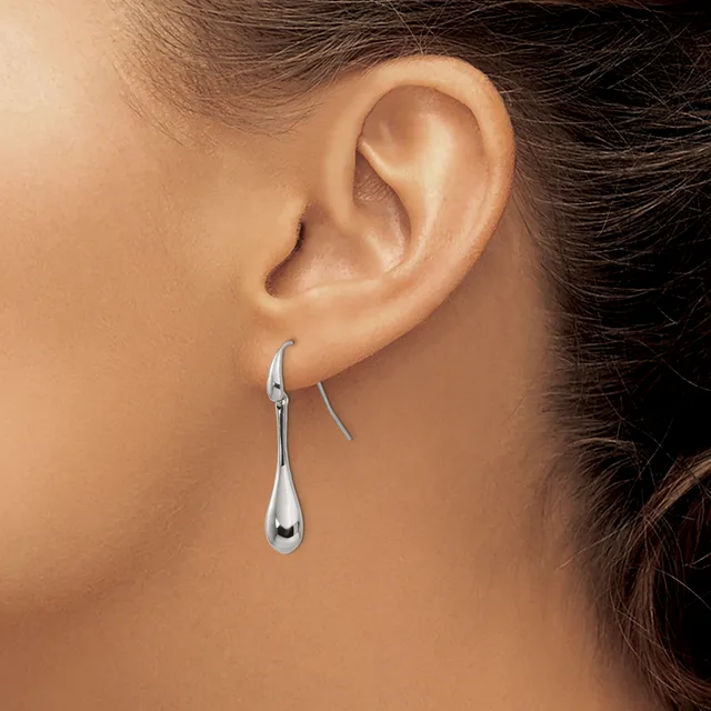 A person wearing a pair of polished silver teardrop-shaped earrings with curved hooks, shown from the side profile view.