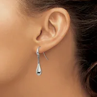 A person wearing a pair of polished silver teardrop-shaped earrings with curved hooks, shown from the side profile view.