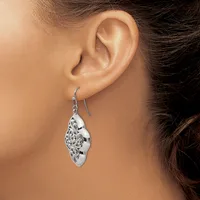 A woman wearing a silver teardrop-shaped earring with an ornate filigree pattern on a fish hook wire, shown from the side view of her ear and neck.