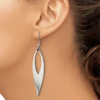 A woman wearing a long, slender silver drop earring with an elongated oval cutout design, shown hanging from her earlobe.