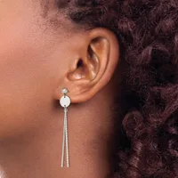 A person wearing a long silver dangle earring with a small disc at the top and two thin chains hanging down, shown from the side profile of their ear.