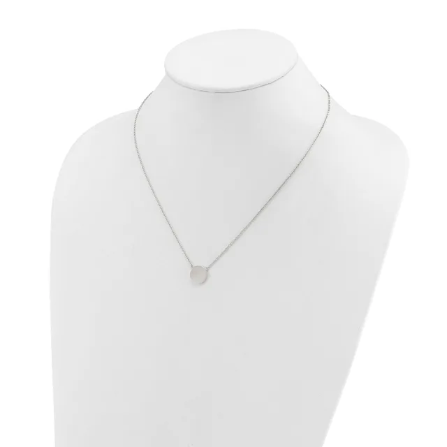 A delicate silver necklace with a small round pendant hanging from a thin chain, displayed on a white bust form.