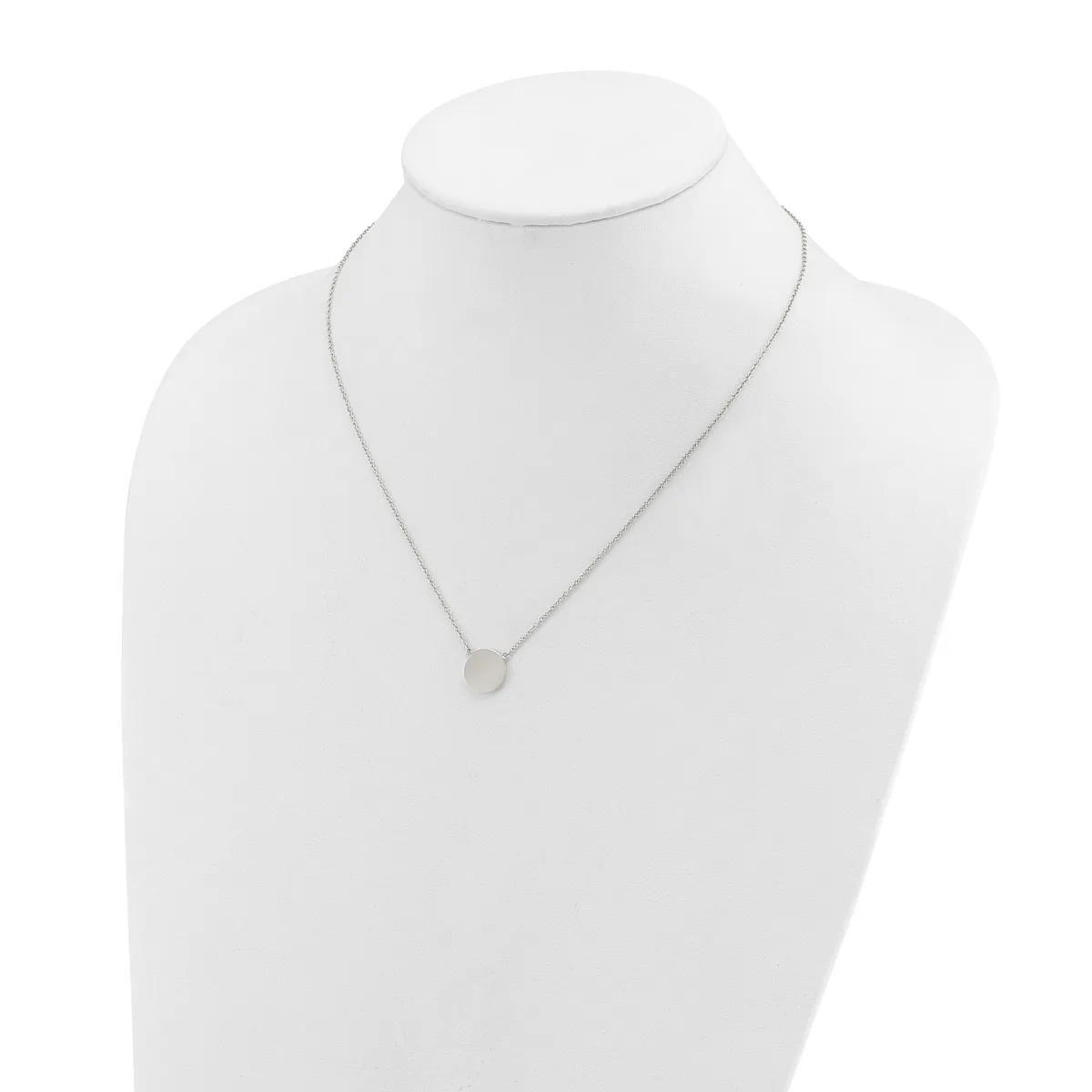 A delicate silver necklace with a small round pendant hanging from a thin chain, displayed on a white bust form.