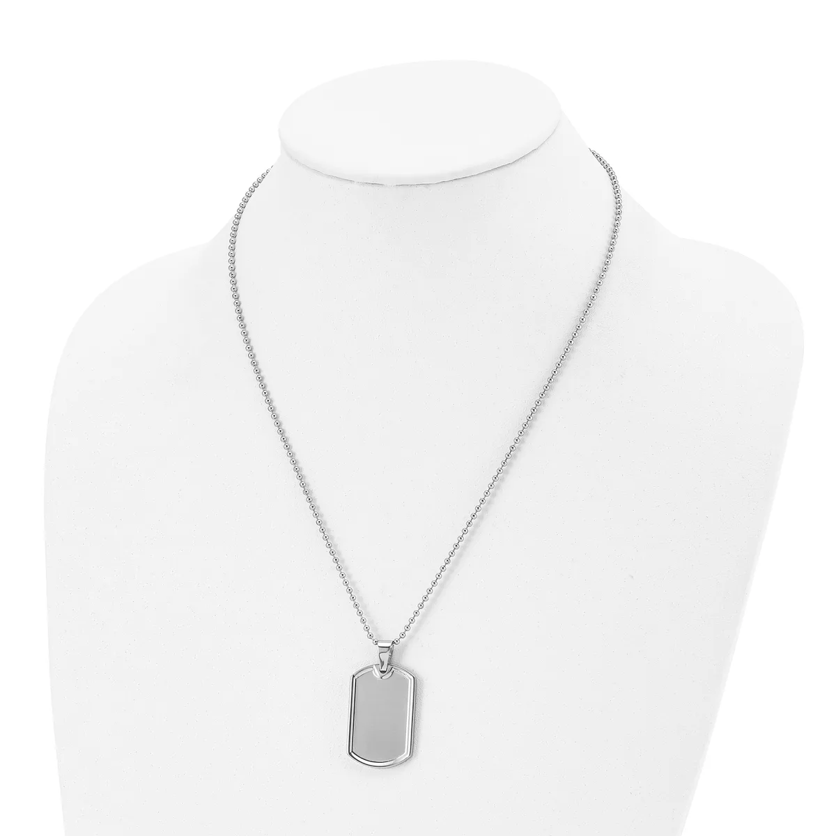 A silver-toned rectangular dog tag pendant hangs from a thin chain on a white mannequin bust.
