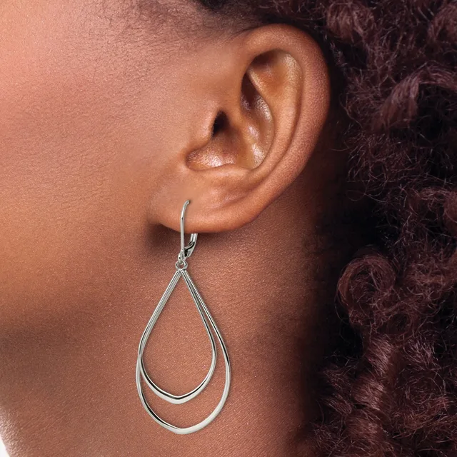 A person wearing a silver teardrop-shaped dangle earring with a hollow double-wire design, shown from the side profile against their neck and shoulder.