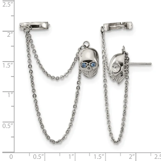 Silver ear cuff pair with dangling chain and skull charms with blue stone eyes, displayed against a ruler showing approximately 2.5 inches in height.