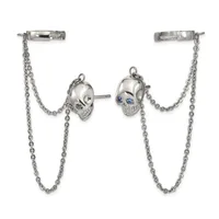 Silver skull stud earrings with blue stone eyes connected by chain drapes to bar ear cuffs.