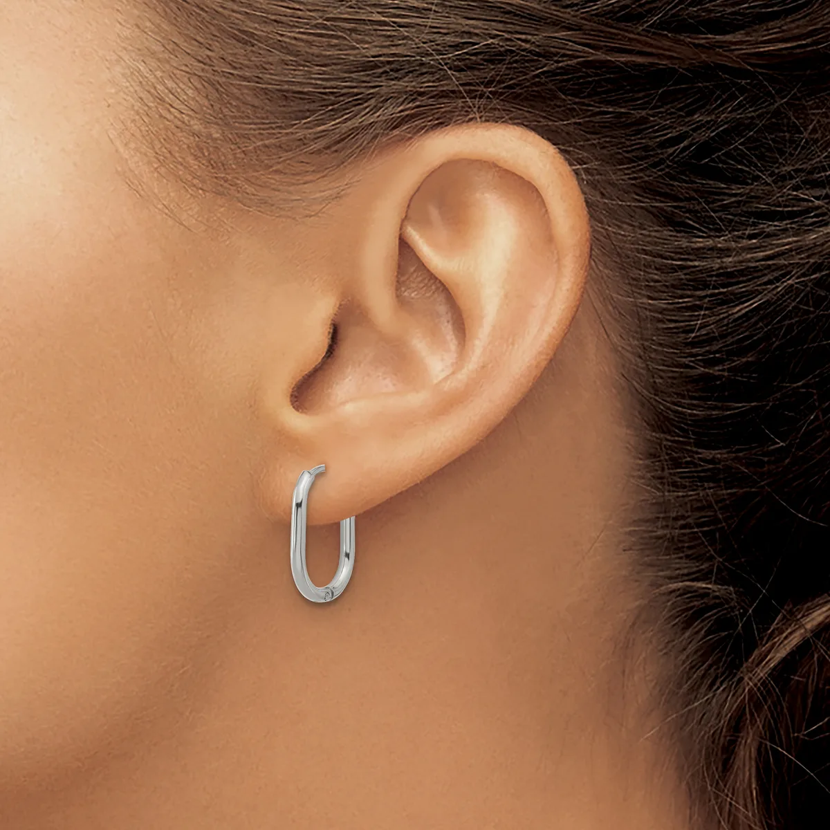 A person wearing a small silver hoop earring in their earlobe, shown from the side profile against their neck and shoulder.