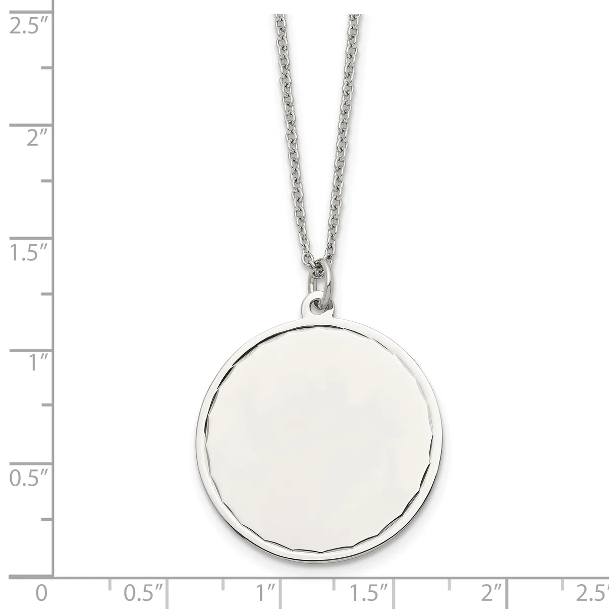 A silver circular pendant with a polished finish hangs from a thin chain, displayed against a ruler showing the pendant is approximately one inch in diameter.