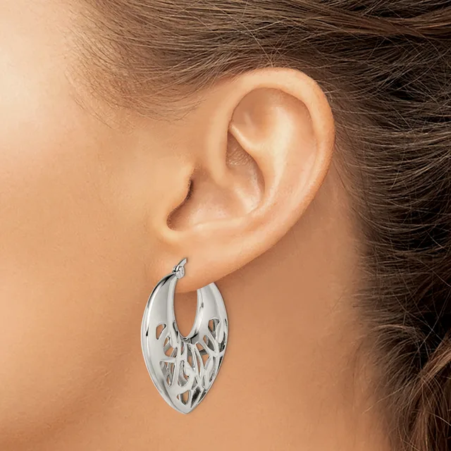 A woman wearing a silver hoop earring with a cutout leaf or feather pattern, shown from the side view of her ear and neck.