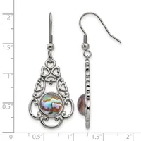 A pair of ornate silver-toned drop earrings with filigree heart designs and iridescent abalone shell centers, displayed on a measurement scale.