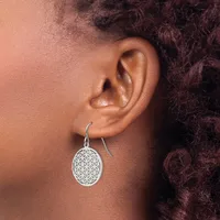 A person wearing a silver drop earring with an oval pendant featuring a geometric flower of life pattern, shown from the side view against their ear and shoulder.