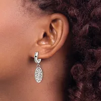 A person wearing a silver hoop earring with an ornate oval filigree pendant hanging from it.