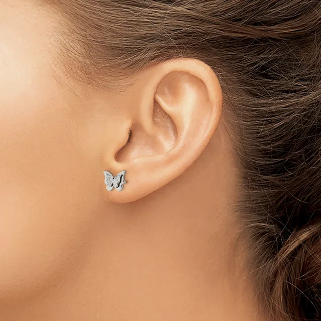 A person wearing a small silver butterfly stud earring in their earlobe, shown from the side profile view.