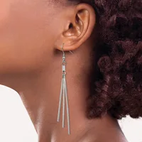 A person wearing a long tapered silver dangle earring with multiple thin strands hanging from a hook fastening, shown from the side profile.
