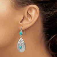 A woman wearing silver teardrop earrings with turquoise stones and filigree detailing, shown from the side profile of her ear and neck.