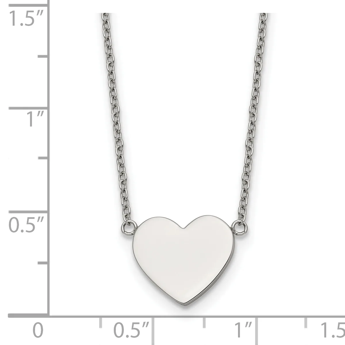 A polished silver heart pendant hangs from two delicate chains against a measurement scale showing the pendant is approximately one inch wide.