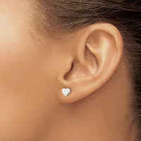 A small white heart-shaped stud earring worn in a person's earlobe, shown from a side profile view.