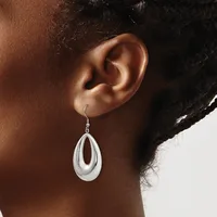 A person wearing a teardrop-shaped silver dangle earring with a polished finish and an open center, shown from the side profile of their ear.