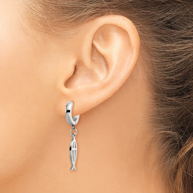A person wearing a silver hoop earring with a small dangling fish charm, shown from the side view near the ear.