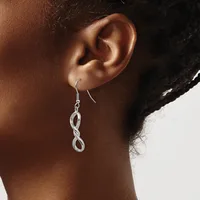 A person wearing a pair of silver twisted loop earrings on fish hook wires, shown from the side against a neutral background.