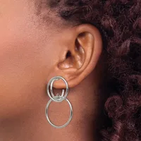 A person wearing a two-tiered silver circular drop earring in their earlobe, shown in profile against their neck and shoulder.