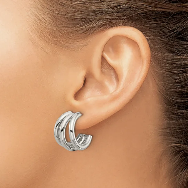 A woman wearing triple-band silver hoop earrings, shown from the side profile of her ear and neck.