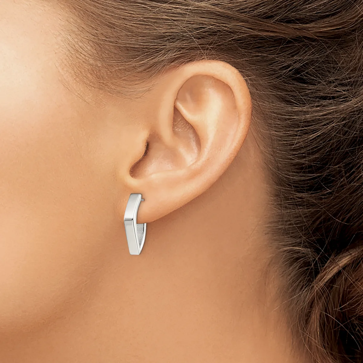 A woman wearing a pair of polished silver rectangular hoop earrings with a squared-off design, shown from the side profile.