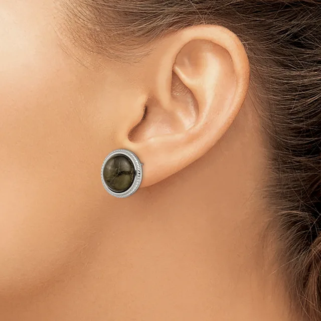 A close-up side view of a person's ear wearing a small oval stud earring with a dark green stone set in a silver-toned metal bezel.