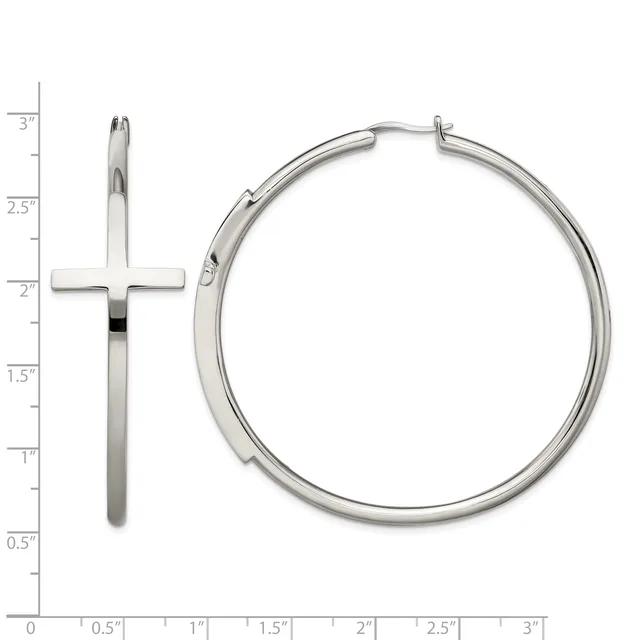 Two silver earrings displayed on a measurement grid: a long cross pendant and a polished hoop earring with a hinge closure.