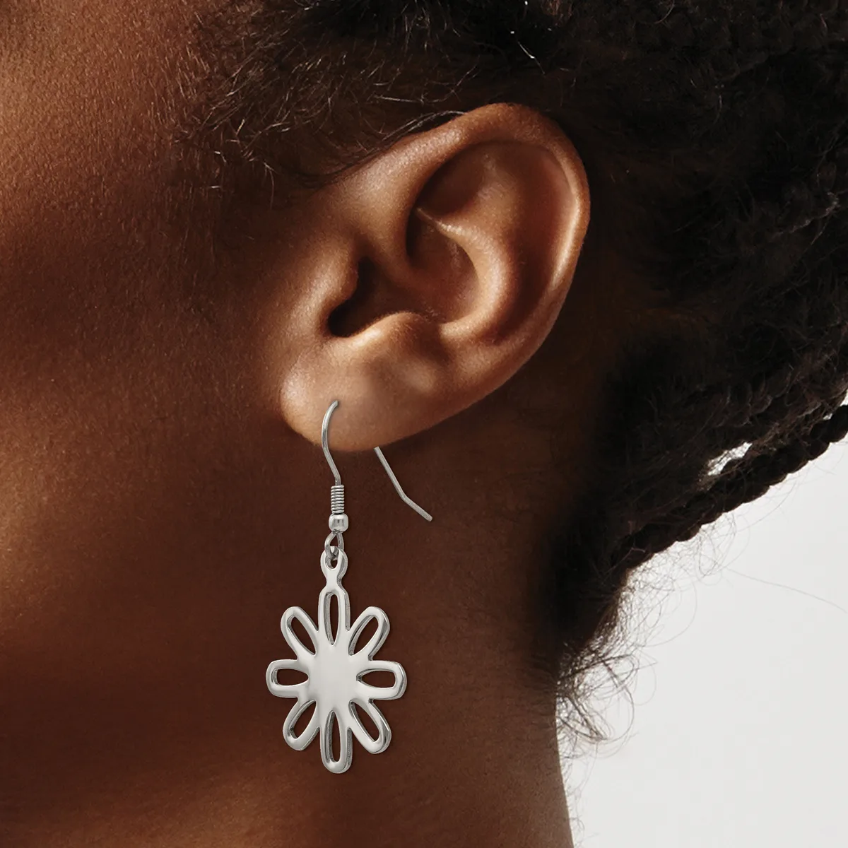 A person wearing a silver flower-shaped dangle earring with looped petals, shown from the side view of their ear against a neutral background.