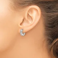 A woman wearing a small textured silver hoop earring in her earlobe, shown from the side view of her head and shoulder.