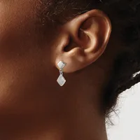 A person wearing a silver drop earring with a square stud top and rectangular pendant hanging below, shown from the side profile of their ear and neck.
