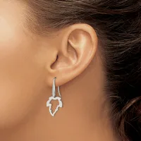 A woman wearing a pair of silver leaf-shaped drop earrings with curved hooks, shown from the side profile of her ear and neck.