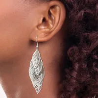 A silver leaf-shaped dangle earring with detailed vein texturing hangs from a curved wire hook on a person's earlobe.