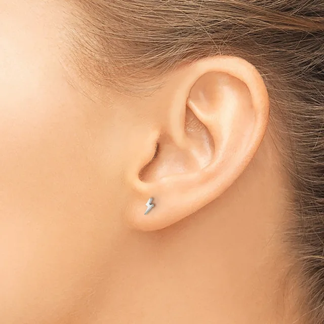 A person wearing a small silver stud earring in their earlobe, shown in profile view against bare skin.