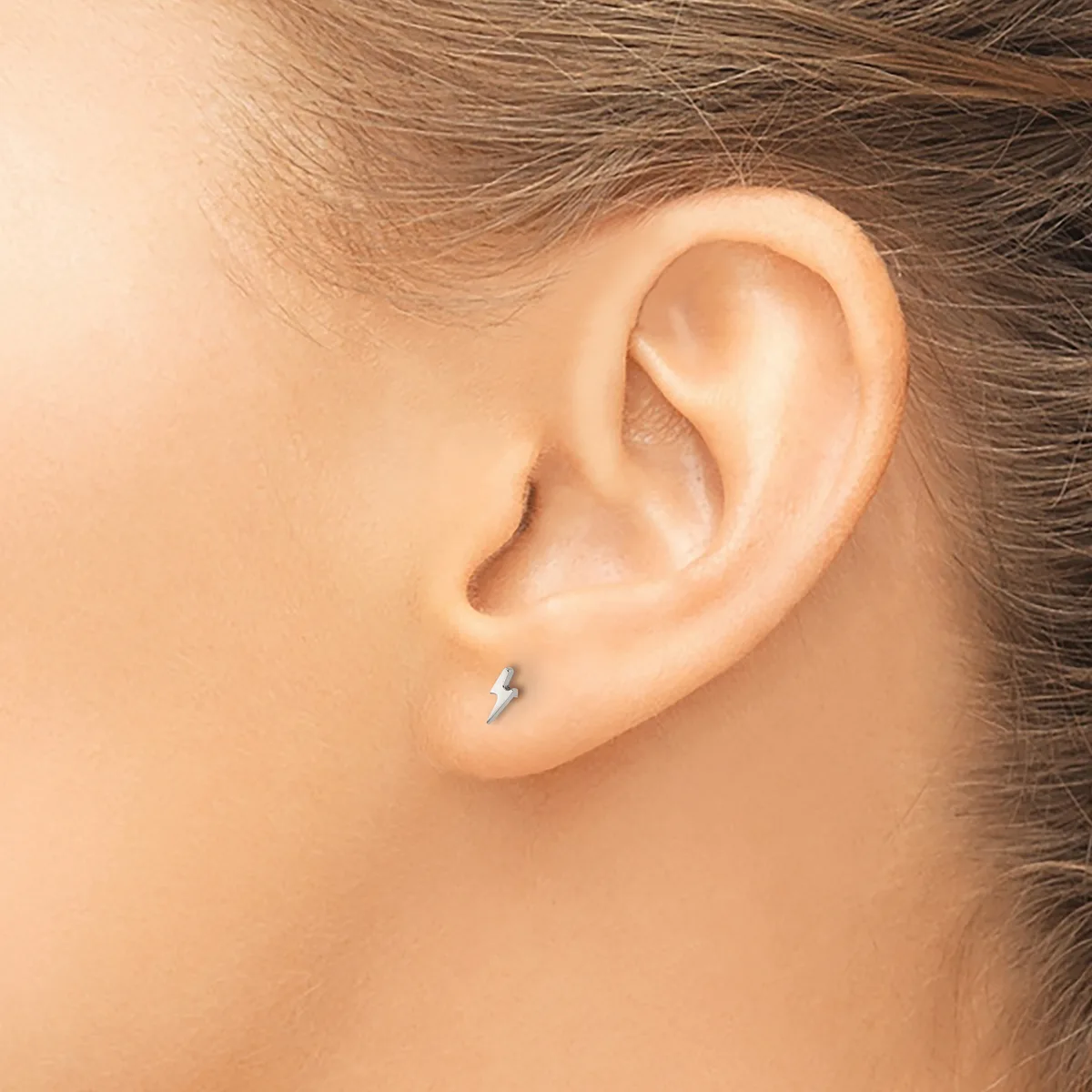 A person wearing a small silver stud earring in their earlobe, shown in profile view against bare skin.