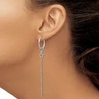 A woman wearing a long dangling silver chain earring with a small hoop connector, shown from the side view against her neck and shoulder.