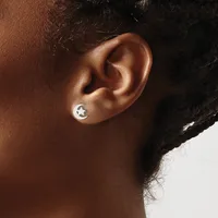 A person wearing a small silver stud earring with a crescent moon design in their earlobe.
