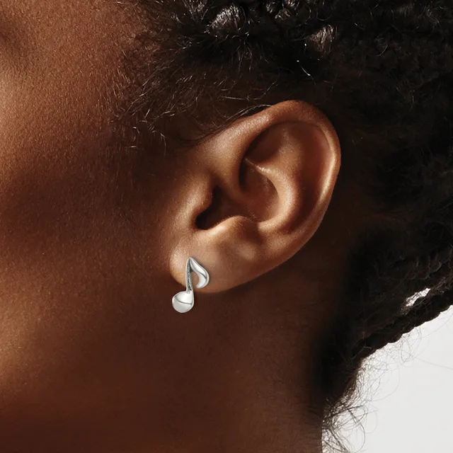 A person wearing silver musical note earrings, shown from the side with their ear and neck visible against a neutral background.