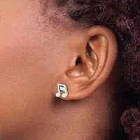 A person wearing a white and black musical note stud earring in their earlobe.