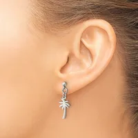 A silver palm tree charm dangle earring worn on a model's ear, shown from the side against a neutral background.