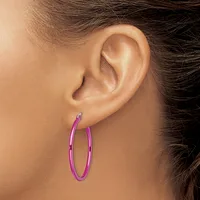 A person wearing a pair of pink metallic hoop earrings with a polished finish, shown in profile view against their ear.