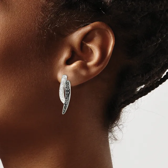 A person wearing a curved silver hoop earring with white and black stones set along the inner surface, shown from the side against a neutral background.