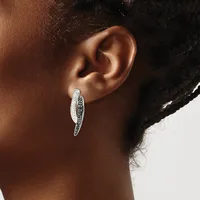 A person wearing a curved silver hoop earring with white and black stones set along the inner surface, shown from the side against a neutral background.